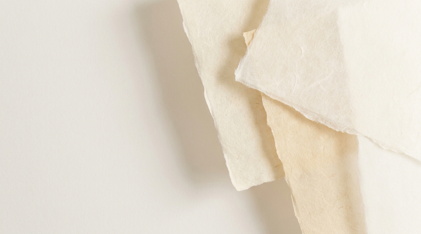 Soft layered sheets of handmade paper against a pale warm background.